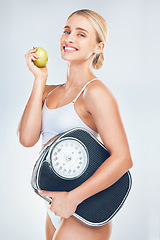 Image showing Health, diet and woman with scale and apple to lose weight for health, wellness and healthy lifestyle as fitness mockup studio background. Portrait, smile and body of model eating fruit for nutrition