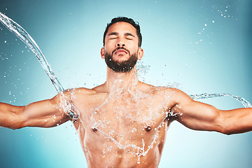 Image showing Muscular man, water splash and wellness for fitness and health with blue studio background. Hygiene, male athlete and bodybuilder wash clean, shower and body care after workout, training and exercise