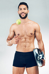 Image showing Fitness, health and man with smile for apple, scale and lifestyle balance against grey studio background. Gym, exercise and portrait of happy, healthy and athlete with fruit for nutrition and weight