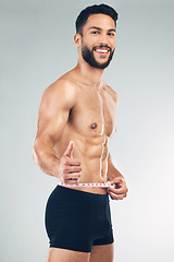 Image showing Body, waist and thumbs up with a man model in studio on a gray background to promote weightloss or exercise. Portrait, fitness and diet with a young male measuring for health, success or motivation