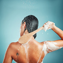 Image showing Skincare, brush and shower by woman in studio for wellness, cleaning and hygiene on blue background mockup. Water splash, hair and back of girl model in beauty splash, water and cleaning in bathroom