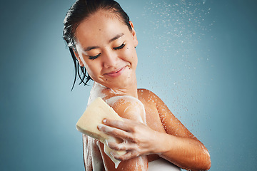 Image showing Woman, water and happy skincare cleaning morning routine or skin wellness treatment with sponge. Young Asian girl washing, relax and healthy hygiene for cosmetic beauty care against blue background