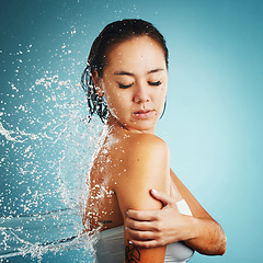 Image showing Water, shower and washing with a woman in studio on a blue background for hygiene or hydration. Cleaning, cleansing and bathroom with an attractive young female in the bathroom for body care