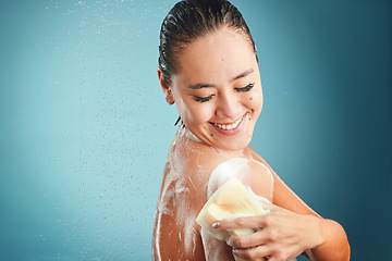 Image showing Shower, sponge and soap with a woman cleaning her body in studio on a blue background with mockup. Water, hand and wellness with an attractive young female washing in the bathroom for hygiene