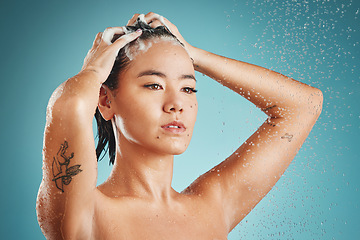 Image showing Asian woman, beauty and shower with water, shampoo and wash against a blue studio background. Female skincare, cleaning and fresh skin, with body wellness, hydration and health with washing hair