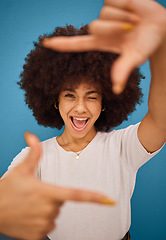 Image showing Black woman, hand frame afro and studio beauty with wink, smile and comic pose by blue background. African model woman, sign hands and funny portrait with happy face, photography and play by backdrop