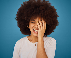 Image showing Face, funny and laughing with an afro black woman in studio on a blue background for fun or humor. Smile, comic and happy with an attractive young female feeling positive with joy or comedy