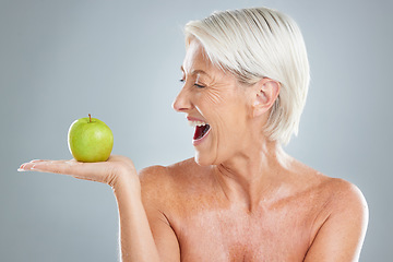 Image showing Beauty, apple and excitement with a senior woman in studio on a gray background to promote healthy eating. Food, fruit and diet with a mature female posing for nutrition vitamins or health lifestyle