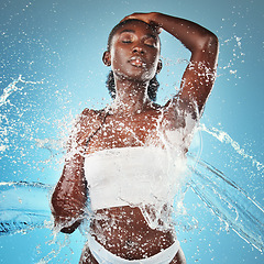 Image showing Woman, water splash and skincare body, beauty moisturiser or hydration by blue background wall. Black woman, skin model and splashes for cosmetics, health or dermatology wellness by cosmetic backdrop