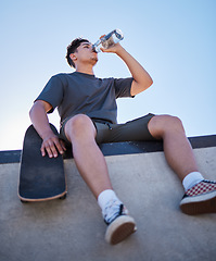 Image showing Skateboard, young man and drinking water bottle, relax and on break on sunny day outdoor. Male, skater and athlete hydrate, thirsty and sports for wellness, health and have fun in summer.