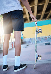 Image showing Legs, skateboard and man at skate park, urban and skating for fun and fitness, trendy and active sport. Skater, sneakers and cool, ready to skate in the city with sunshine and hipster with off ramp.