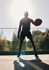 Image showing Basketball, sports and man in a park for training, cardio and exercise with a ball during summer. Dark silhouette of a professional athlete with freedom and energy for a sport on a basketball court