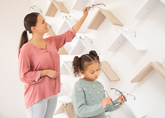 Image showing Glasses, decision and mother and child at an optometrist clinic for choice of frame for vision together. Optometry, smile and girl and mom with eyeglasses for eyes as a customer choosing in a store