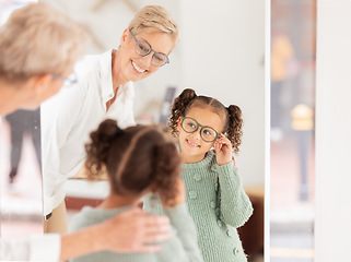 Image showing Glasses, vision and children with a girl and woman optician looking in a mirror during an appointment or checkup. Eyewear, optometry and frame with a child customer shopping for prescription lenses