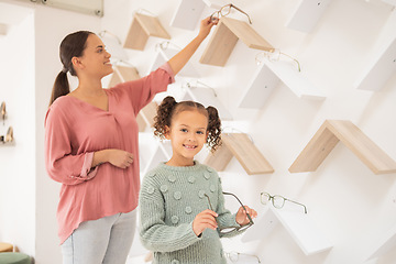 Image showing Optometry, mother and child with decision on glasses for vision, smile and help with eyes at a clinic. Happy, consulting and girl kid patient at the optometrist for eyeglasses with her mom helping