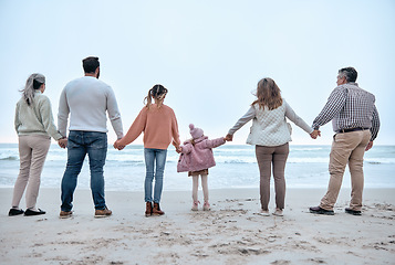 Image showing Family holding hands, beach and adventure with love, trust and relationship, outdoor bonding by the ocean. Parents, grandparents and children, together and travel to the sea for quality time.