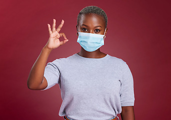 Image showing Black woman, covid and ok sign with face mask for approval, yes and safety with hand gesture for health and wellness. Portrait of African model for covid 19, corona and virus compliance in studio