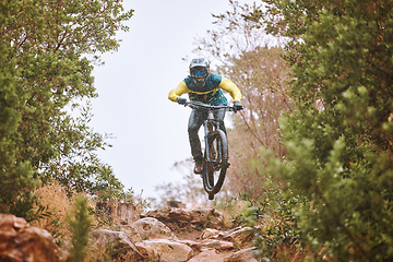 Image showing Mountain bike, sports and fitness with a man adrenaline junkie riding in the woods or forest in nature. Sky, training and exercise with a male athlete on a bike for trail riding or adventure