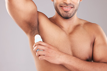 Image showing Deodorant, underarm and grooming with a man model in studio on a gray background for hygiene or scent. Wellness, cosmetics and body with a male applying rollon to promote a product for fresh aroma
