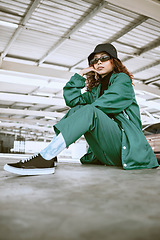 Image showing Fashion, style and portrait of woman in parking lot with trendy, stylish and designer clothing. Beauty, freedom and black woman in sitting pose on floor of car park in cool, edgy and urban outfit