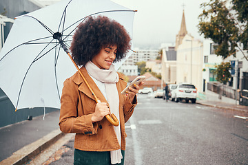 Image showing Black woman, winter on city street and smartphone in hand browsing social media, online conversation and umbrella in hand waiting for taxi in rain. Mobile GPS technology, happy smile and cell message