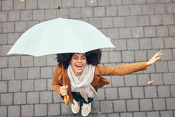 Image showing Black woman, umbrella and rain with smile, happy and enjoy weather in city being wet. Winter, young female and happiness for storm, cheerful and joyful with cover, comfortable and rainy outdoor.