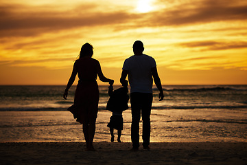 Image showing Silhouette, beach and family at the sea at sunset, holding hands and playing, bonding and relax together. Shadow, happy family and child with parents at sunrise, travel, freedom and love in Bali