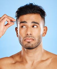 Image showing Face, hair removal and man in studio with tweezer for skincare, beauty and eyebrow on blue background. Tweezing, wellness and indian model shape eyebrows for grooming, hygiene and cleaning on mockup