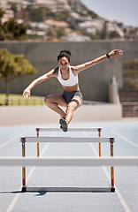 Image showing Fitness, training and woman jumping hurdles for sports, exercise and intense cardio on a running track. Black woman, running and hurdling workout for speed, energy and physical performance at stadium