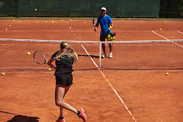 Image showing A professional tennis player and her coach training on a sunny day at the tennis court. Training and preparation of a professional tennis player