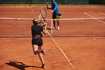 Image showing A professional tennis player and her coach training on a sunny day at the tennis court. Training and preparation of a professional tennis player