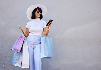 Image showing Shopping, phone and woman in the city for fashion sale, discount and fun against a wall background mockup. Girl, shopping bag and online search on social media for promo code, retail news and mock up