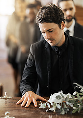 Image showing Sad, funeral and coffin with man in church for death, mourning and respect at burial ceremony. Flowers, depression and grief with family goodbye at casket in chapel for loss, remember and sorrow