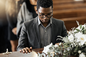 Image showing Funeral coffin, death and black man sad, grieving and mourning loss of family, friends or dead loved one. Church service, floral flowers and person with casket, grief and sadness over loss of life