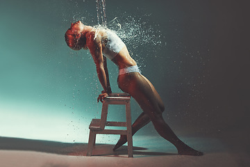 Image showing Water, sexy and chair with a woman in studio or on stage during a theatre show for entertainment. Splash, performance and wet with an attractive young female on a color background for theater