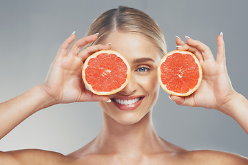 Image showing Grapefruit, skincare and face of a woman with smile for health, wellness and healthcare with food against a grey studio background. Nutrition, happiness and model with fruit for body detox and diet