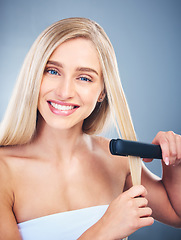 Image showing Portrait of blonde happy woman, flat iron aesthetic for beauty salon and healthy hair care with natural smile. Young model with clean hair shine, studio with blue background and cosmetic heat tool