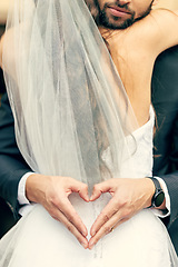 Image showing Hand, heart and bride and groom hug at their wedding, happy and relax while sharing an intimate moment. Hands, love and couple celebrate their marriage, embrace and having fun while showing emoji