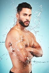 Image showing Splash, water and man in hygiene and cleaning portrait, washing body and skin hydration with blue studio background. Topless model wet, skincare and grooming, fresh and clean with wellness.