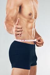 Image showing Fitness, thumbs up and man measuring body after training, workout and exercise. Healthy, wellness and strong muscular male with measuring tape on waist for diet, weight loss and body care in studio