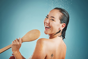 Image showing Woman, singing and shower in studio for wellness, skin and body care on a blue background, happy and relax. Singer, bathroom and water splash karaoke by portrait of asian girl having fun and grooming