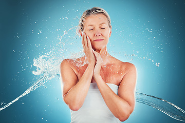 Image showing Water, splash and mature woman washing her body on a blue studio background for care and hygiene. Beauty, grooming and shower with a older female cleansing her skin for skincare and bodycare