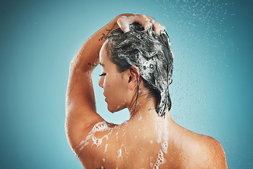 Image showing Beauty, shower and woman cleaning, haircare and shampoo while washing against a blue studio mock up background. Back, model and clean in bathroom for skincare, health and wellness with water and soap