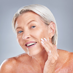 Image showing Skincare, wellness and senior woman with face for inspection, health and beauty against a grey studio background. Happy, smile and portrait of an elderly person with facial care during retirement