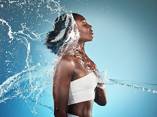 Image showing Water, splash and woman washing her body on a blue studio background for cleansing hygiene. Cleaning, wash and african american female using grooming treatment for hydration and bodycare