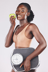 Image showing Apple, scale and weightloss with a black woman in studio on a gray background to promote healthy eating or diet. Food, fruit and exercise with an attractive young female posing for natural vitamins