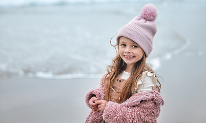 Image showing Happy girl child on beach, portrait on winter holiday with pink beanie and kid smile on the Dublin seaside. Outdoor freedom on ocean break, cute toddler relaxing by the water and coastal peace