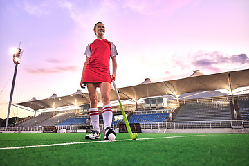 Image showing Sports, hockey and girl in outdoor stadium ready for game, match and practice in evening. Fitness, motivation and young woman on field with hockey stick and ball, doing exercise, workout and training