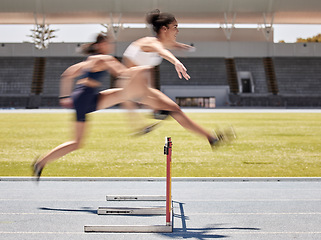 Image showing Woman, sports and hurdle athletics running for exercise, training or workout at the stadium track outdoors. Fitness women athletes in competitive sport jumping over hurdles for healthy cardio outside