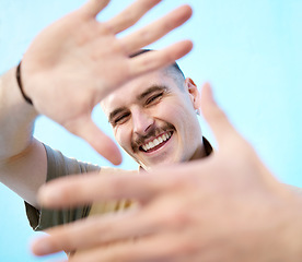 Image showing Hands frame, portrait and smile of man in studio isolated against a blue background. Face, fashion and happy, comic and smiling carefree male with hand sign or gesture enjoying quality time alone.
